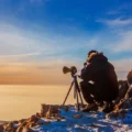 photographe en montagne sur la neige au dessus des nuages