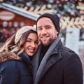 couple posant devant un marché de Noël en hiver