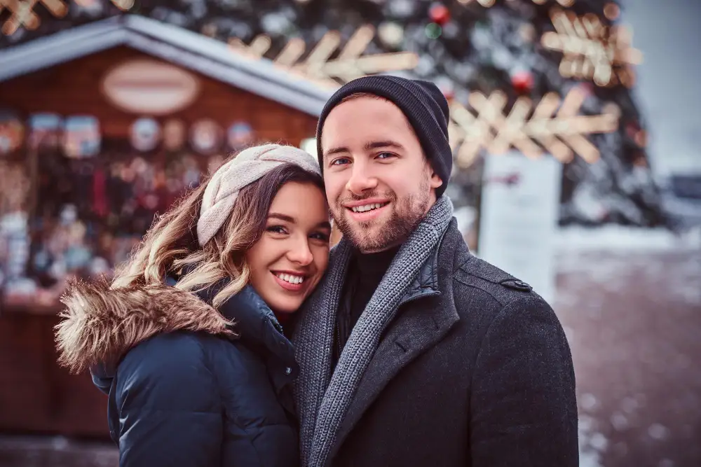 couple posant devant un marché de Noël en hiver