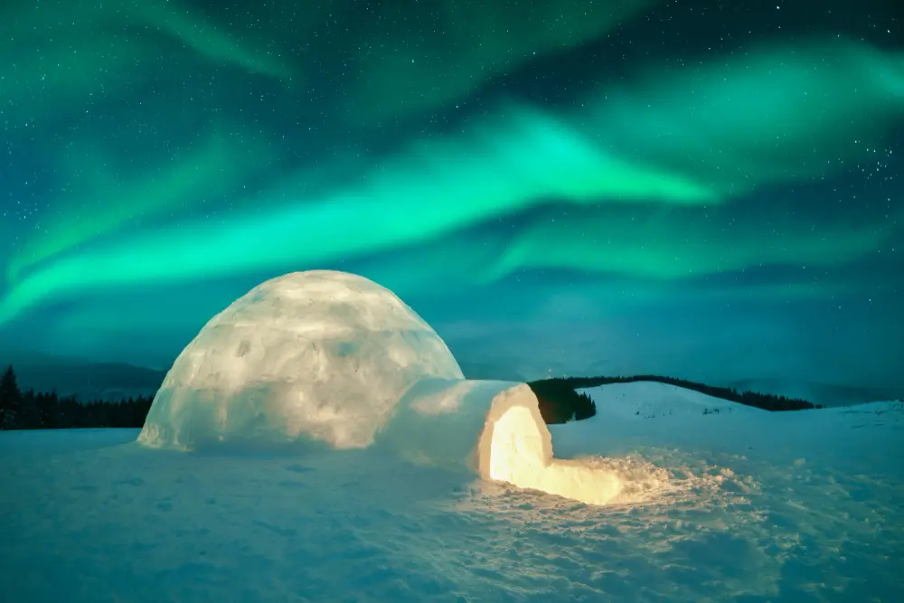 igloo illuminée sous des aurores boréales